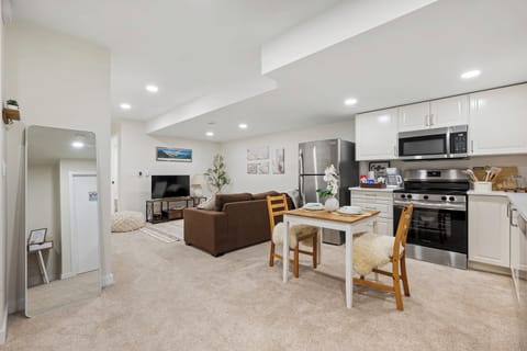 Bright open living space with Smart TV, cozy sofa, dining nook, and full kitchen