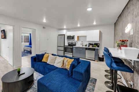 Modern open living space with bold blue sofa, full kitchen, and breakfast bar