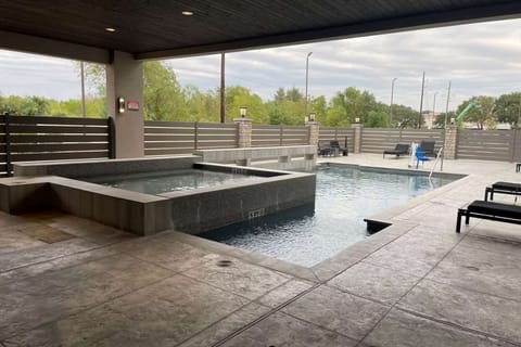 Pool area with spa, lounge chairs, and fenced surroundings