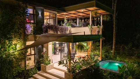 Exterior at night with illuminated pool and tropical outdoor living spaces.