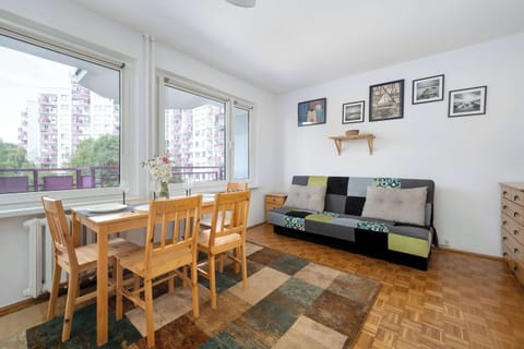 Bright bedroom with a dining table, TV, comfortable seating, and large windows letting in plenty of natural light.
