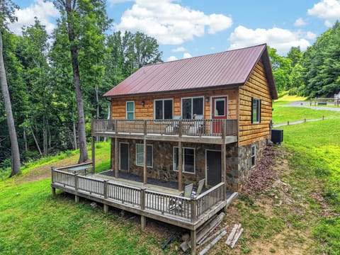 A two-story log cabin with a stone lower level, featuring multi-tiered wooden decks.