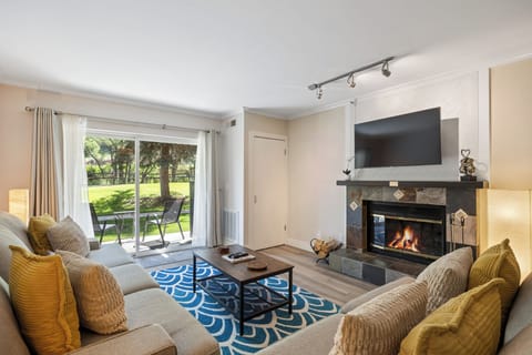 Relax in the inviting living room featuring plush seating, a cozy fireplace, Smart TV, and sliding glass doors that open to a private patio with peaceful outdoor views.