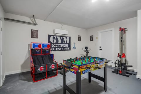 Fun game room with foosball, arcade hoops, and home gym setup