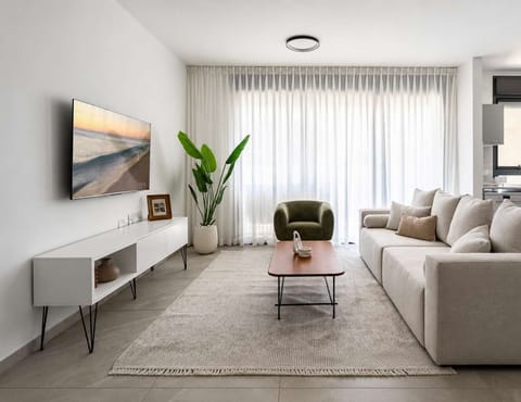 Refined lounge anchored by moss-green accent chair, natural illumination, and sophisticated entertainment setup.
