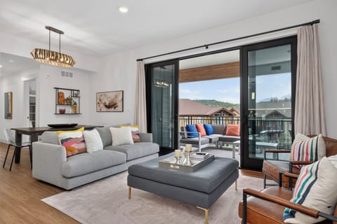 Sink into the plush sofa and let natural light fill your bright, open living space as you gaze out at mountain views through expansive glass doors leading to your private balcony.