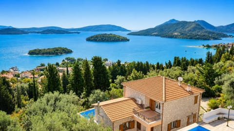 Stone villa with a tiled roof overlooking a scenic bay with green islands.