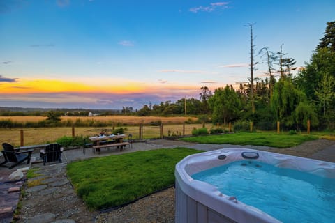 Outdoor patio and hot tub overlooking a scenic rural landscape at sunset.