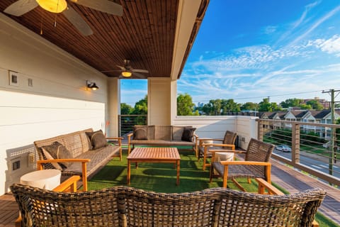 Covered rooftop deck with lounge seating, turf flooring, and neighborhood views.