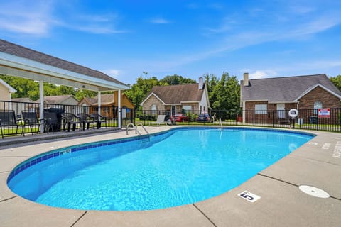 Outdoor swimming pool surrounded by residential units and lush greenery, offering a peaceful communal space within the property grounds.