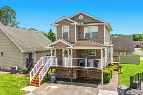 Charming two-story home features a welcoming front porch and manicured lawn, situated in a peaceful neighborhood with mature trees and mountain views in the distance.