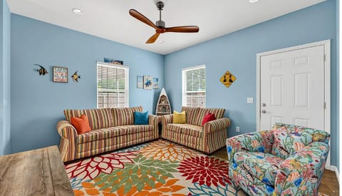 Unwind in your bright living room with playful coastal charm, striped sofas, and a vibrant rug—perfect for relaxing after beachside adventures.