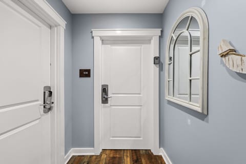 Your private hallway welcomes you with soothing coastal blue walls and polished hardwood floors, featuring secure keyless entry to your numbered suite and charming architectural details that blend comfort with classic elegance.