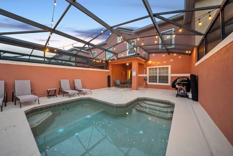 Step outside to your private oasis, featuring a sparkling pool surrounded by cozy lounge chairs and soft string lights for a warm ambiance. The vibrant orange walls enhance this cheerful retreat, ideal for relaxation.