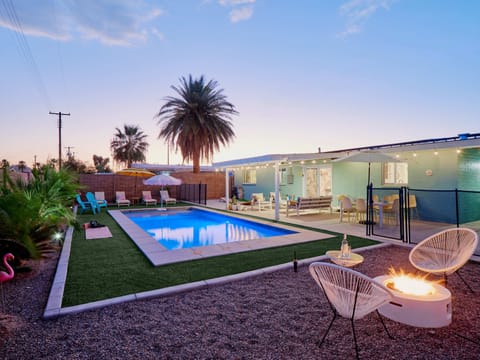 Private backyard oasis featuring a sparkling pool, fire pit lounge, shaded outdoor dining, poolside seating, cornhole, basketball, and a putting green.