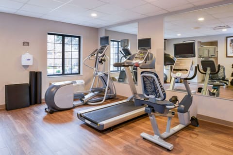 Fitness area featuring ellipticals, treadmill, and mirrored walls.