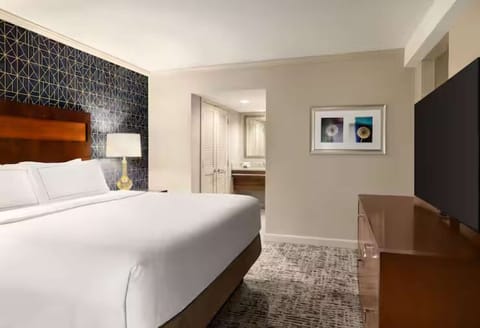 King bedroom with accent wall and dresser television setup