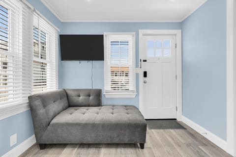 Bright, stylish entry lounge with chaise seating and wall-mounted TV