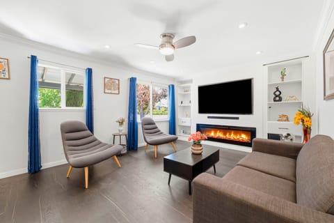 Bright modern lounge with fireplace, large TV, and stylish seating