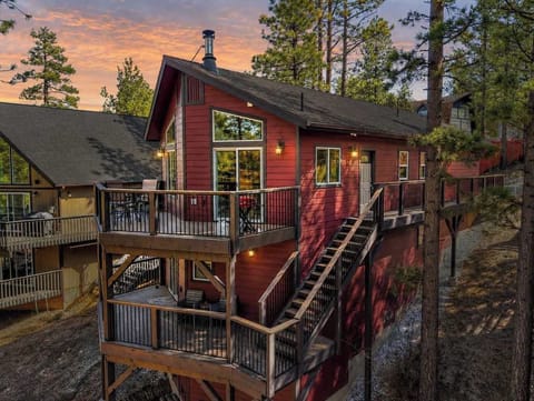 Hilltop cabin surrounded by pines with multiple outdoor living spaces.