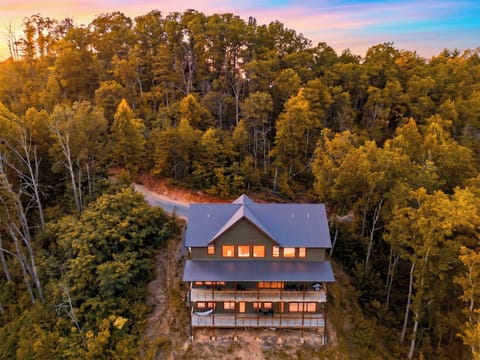 Aerial drone shot of the entire property glowing warmly during a colorful sunset.