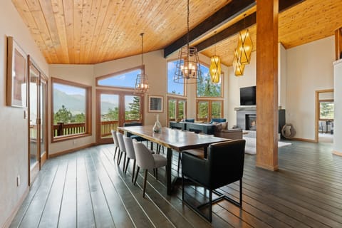 Gather around the elegant dining table under vaulted wood ceilings, where mountain views frame every meal and modern pendant lighting sets a warm, inviting ambiance for your group.