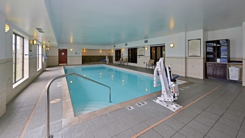 Indoor pool area with railing and poolside seating.