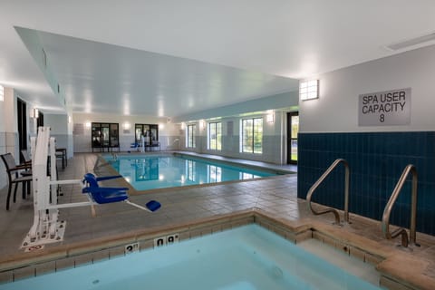 Blue tile accents line the spa entrance beside a full-length indoor pool with poolside seating.