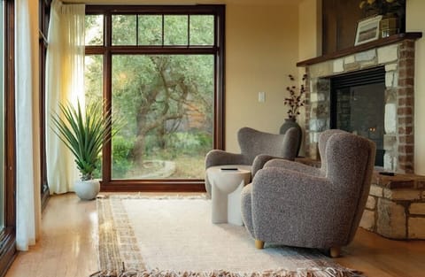 Sink into sculptural lounge chairs beside a two-sided fireplace, with views of native oaks through floor-to-ceiling windows. Whether enjoying morning coffee or an evening glass of wine, this fireside nook is an unforgettable hideaway.