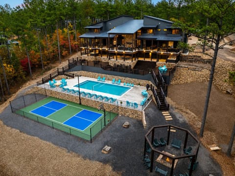 Aerial view of Inspiration Point with a large heated pool, private lighted pickleball court, outdoor fire pit, spacious decks, and mountain views.