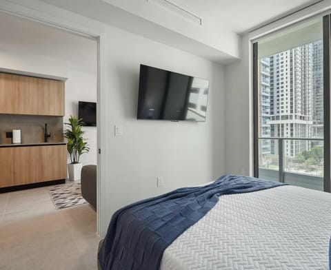 Bright queen bedroom with floor-to-ceiling windows and open city views