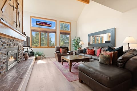 Stretch out on plush leather sofas beside a cozy stone fireplace while natural light pours through soaring windows framing mountain views. Your perfect retreat for relaxing evenings.