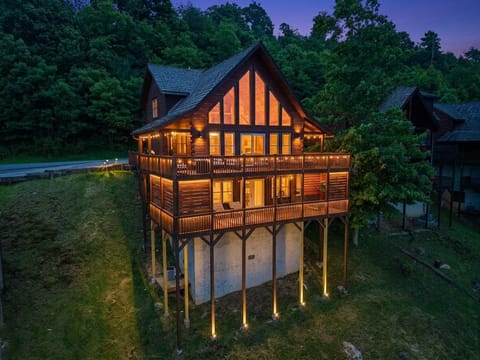 All lit up at dusk with the mountains going dark behind it — this cabin looks like a dream from the outside too.