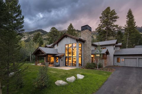 Timber and stone details define the front of the home at dusk.