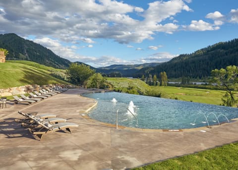 The seasonal infinity-edge pool opens to open meadow and mountain skyline — open Memorial Day through Labor Day