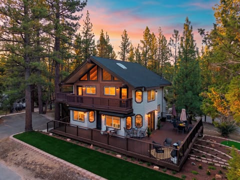 A spacious mountain retreat framed by towering pines, with wraparound decks and inviting outdoor gathering spaces.