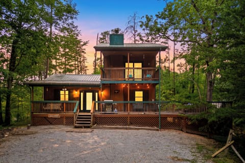 Front view of the cabin during a vibrant sunset with warm lighting inside.
