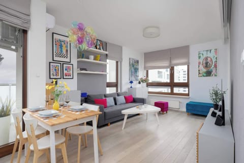 A spacious open plan living and dining area with modern furnishings. Large windows make the interior bright and inviting.
