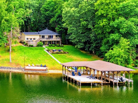 Dock & Boathouse - An aerial view of the home, the lawn sloping to the shore, and the covered boathouse dock.