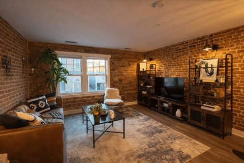 Exposed-brick living room with leather seating and smart TV
