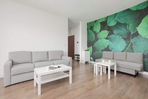 Bright living room with a comfortable sofa, armchair, and stylish green feature wall.