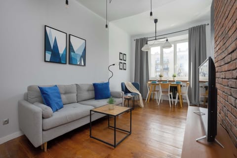 A bright living room with a comfortable sofa, coffee table, and dining area by the window. It is a cozy space to relax and enjoy time with your loved ones.