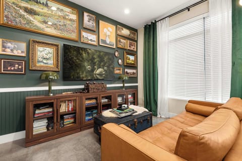 Gallery wall and glass-front bookshelves flank the mounted TV