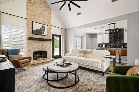 Elegant living room with plush seating, a warm fireplace, and seamless flow into the kitchen—ideal for relaxing, entertaining, or enjoying a quiet evening at home.