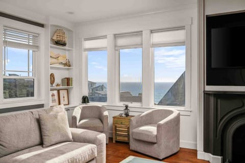 A cozy coastal living space with plush seating, ocean views, and a feature fireplace.