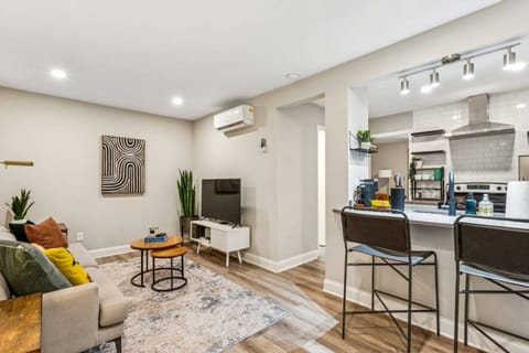 Relax in this bright, open-concept living space featuring a cozy lounge, smart TV, and a fully equipped kitchen with bar seating.