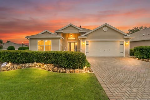 A welcoming property nestled in a peaceful neighborhood, framed by manicured landscaping and glowing warmly beneath a stunning sunset sky.