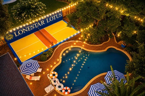 Resort-style pool, lit sport court, and glowing outdoor oasis at twilight