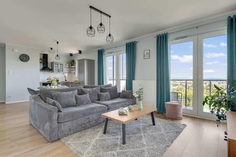 Sercem apartamentu jest jasny salon połączony z aneksem kuchennym i częścią jadalnianą. W salonie znajduje się duża, wygodna sofa, stolik kawowy oraz telewizor, dzięki czemu przestrzeń świetnie sprawdzi się do wspólnego odpoczynku.