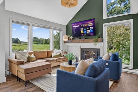 Bright, welcoming living room with golf course views, comfortable seating, a Smart TV, and a wood-burning fireplace.